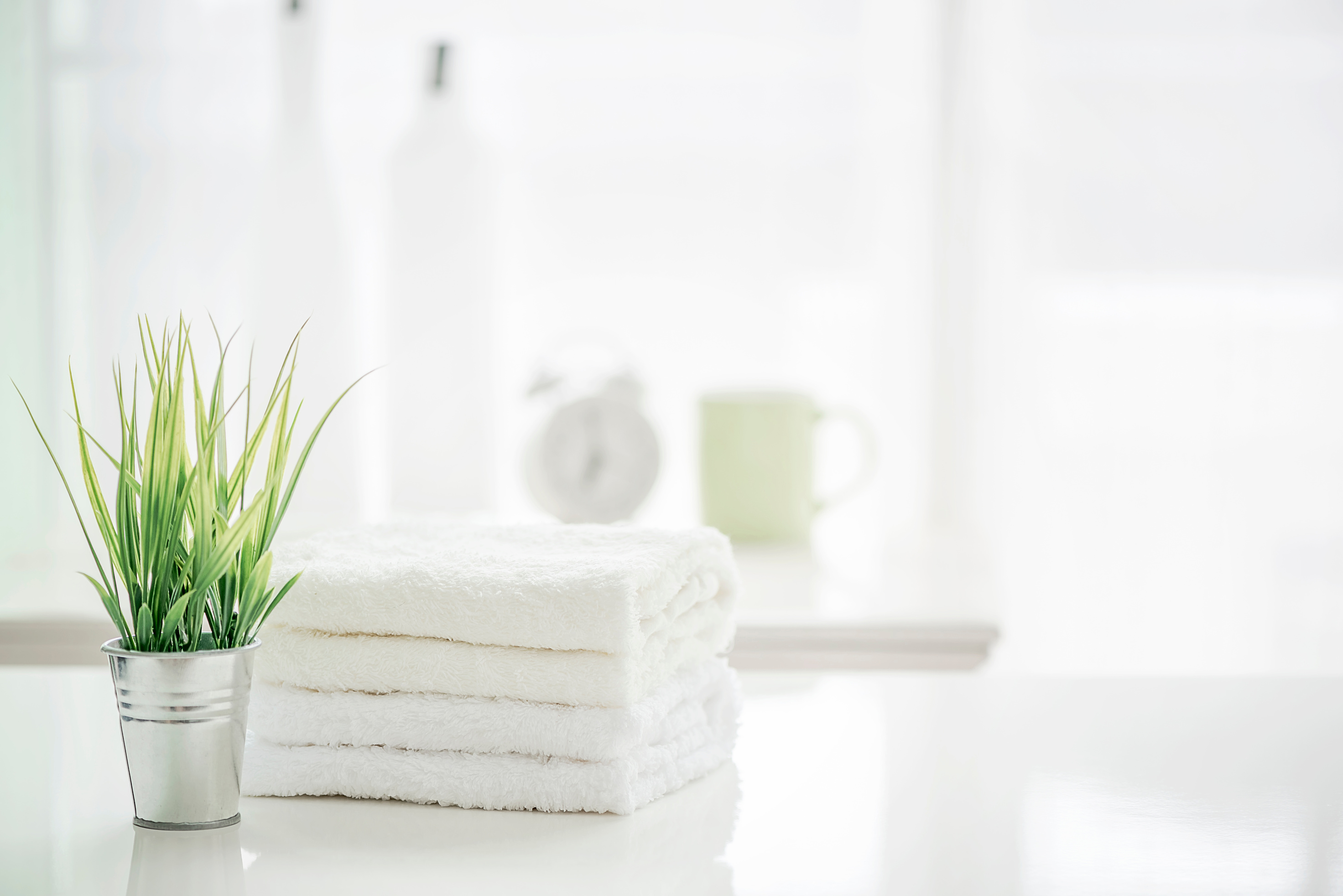 Towels on white table with copy space on blurred bathroom background